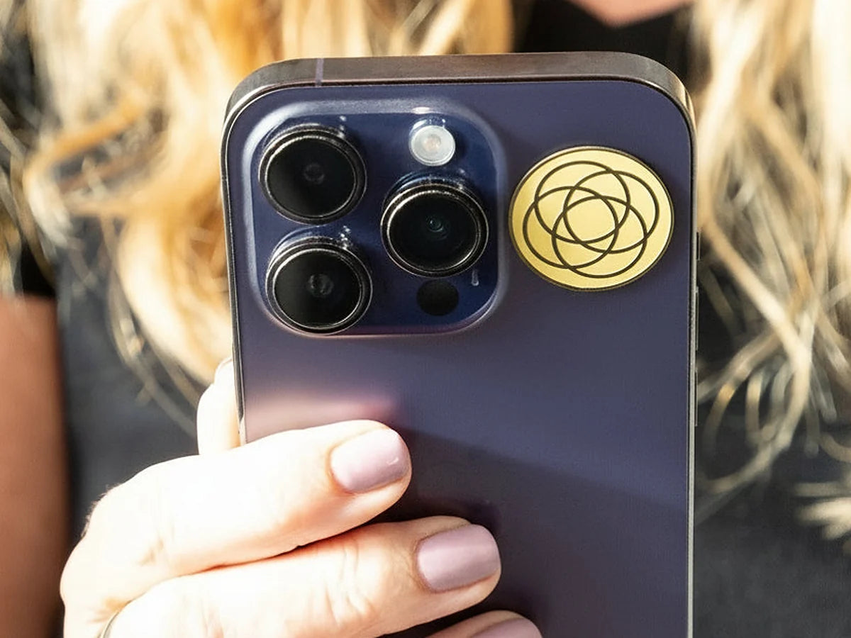 Gold Harmoni sticker on the back of a phone, beside the camera