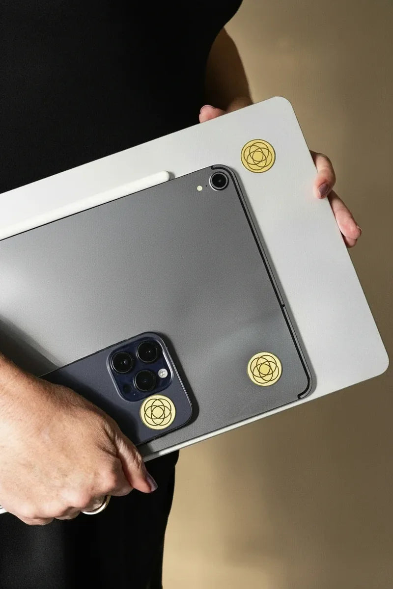 Harmoni EMF stickers applied to a phone, tablet, and laptop