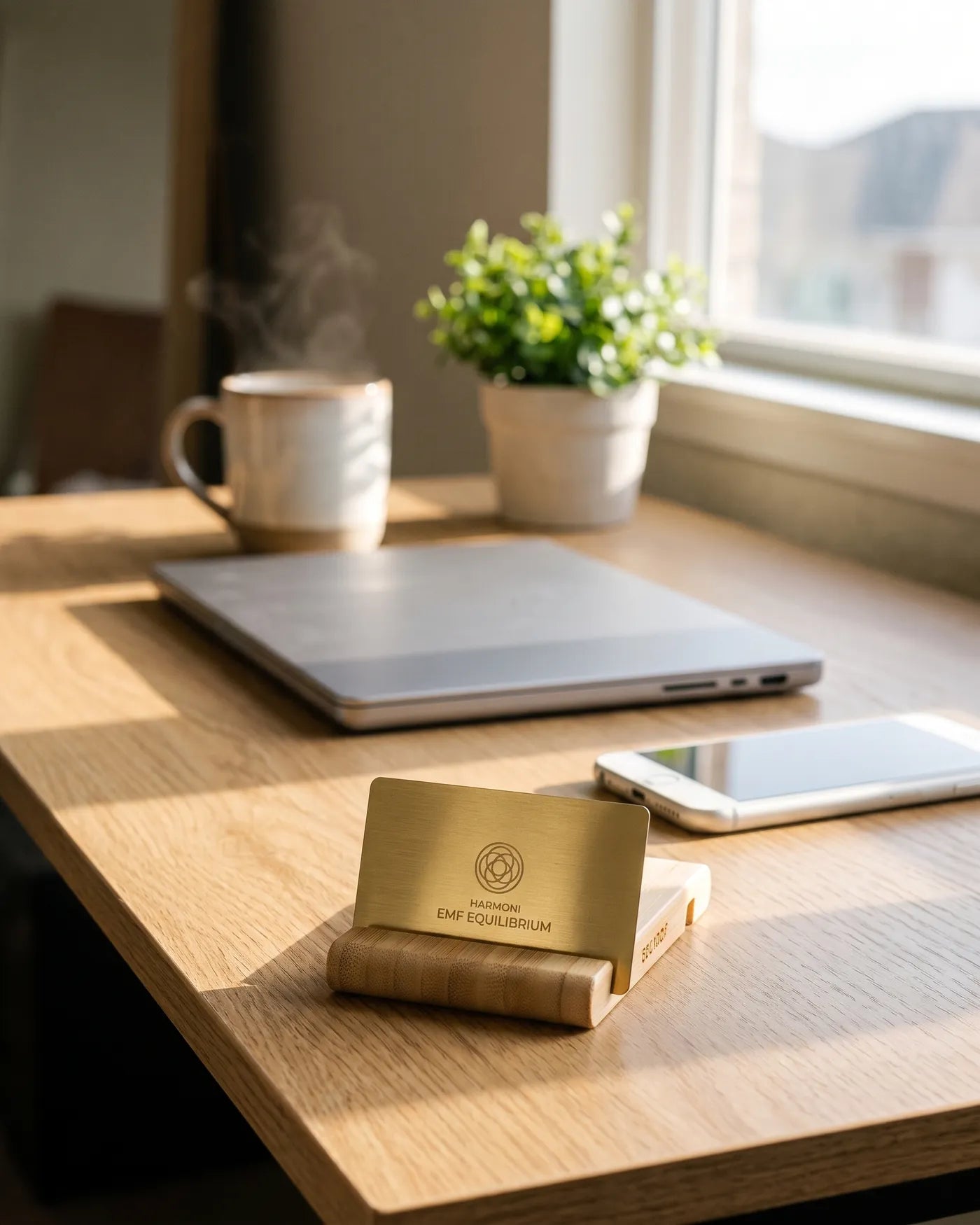 Harmoni EMF Equilibrium Card standing in its wooden stand on a sunlit home-office desk