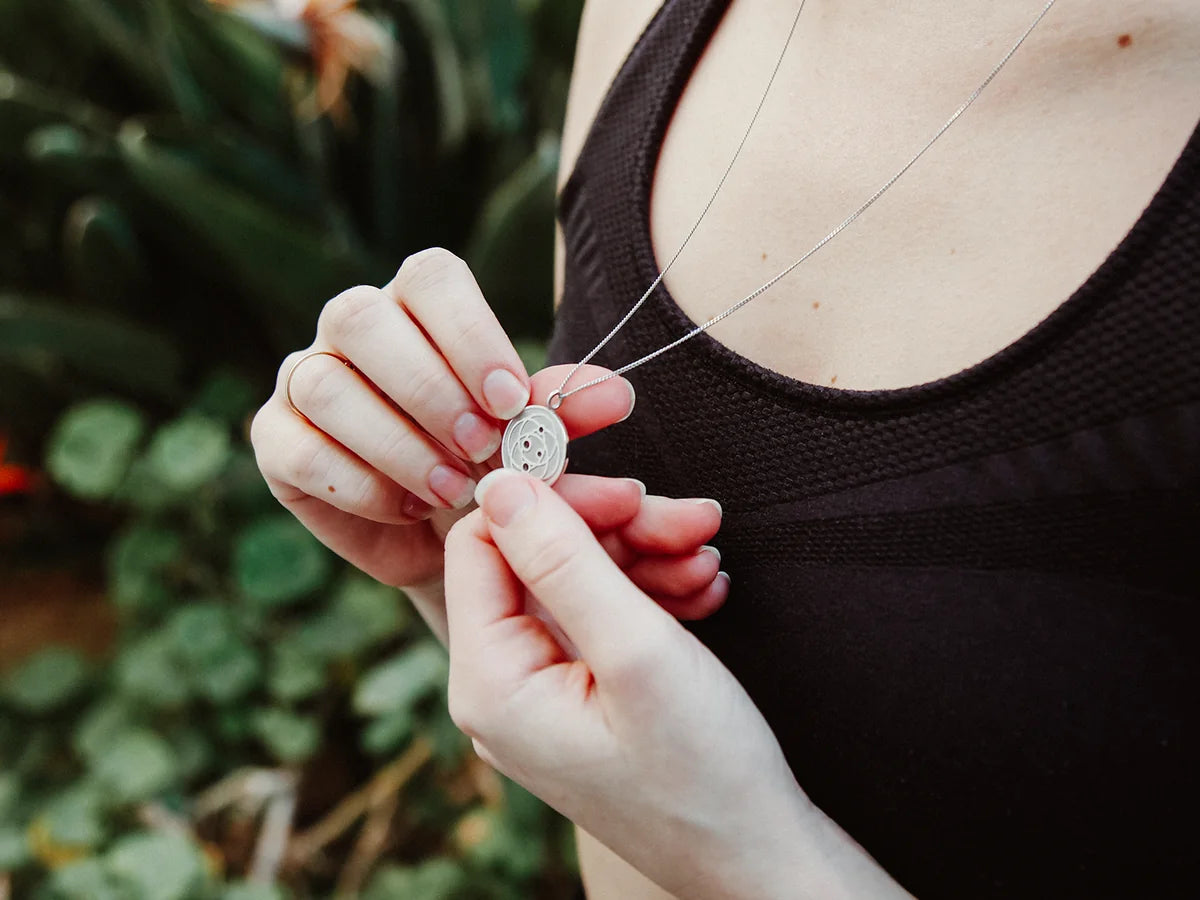 Woman holding a stainless Harmoni Pendant on its chain